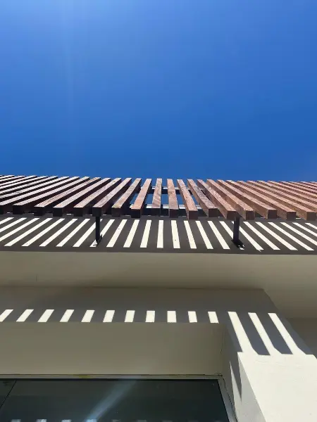 Detalhe do ripado de madeira na fachada executada, projetando sombras sobre a parede clara