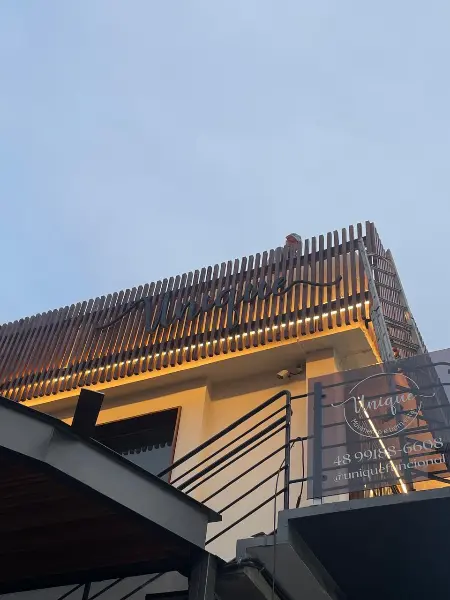 Fachada executada da UNQ vista de baixo, com ripado de madeira e letreiro